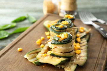 Tasty zucchini rolls with corn on wooden board