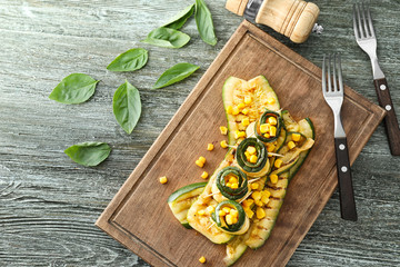 Tasty zucchini rolls with corn on wooden board