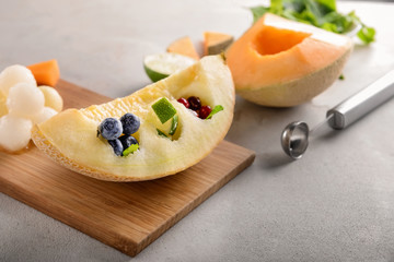 Delicious melon with berries on grey table