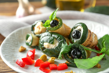 Plate with tasty zucchini rolls on wooden table, closeup