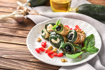 Fototapeta na wymiar Plate with tasty zucchini rolls on wooden table