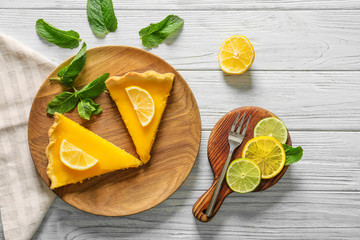 Composition with pieces of tasty lemon pie on light wooden table