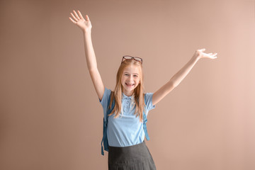 Happy schoolgirl with backpack on color background