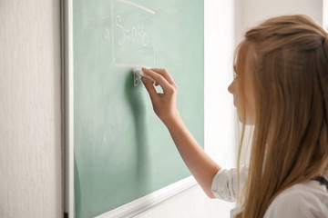Cute schoolgirl writing with chalk on blackboard © Pixel-Shot