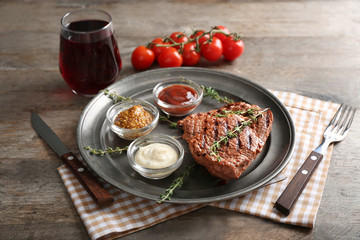 Tasty grilled steak with different sauces on metal tray