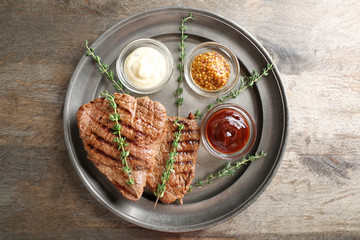 Tasty grilled steak with different sauces on metal tray