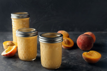 Jars with fresh peach smoothie on grey table