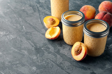 Jars with fresh peach smoothie on grey table