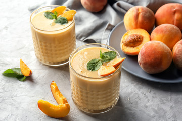 Glasses with fresh peach smoothie on light table