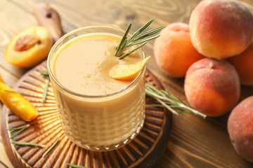 Glass with fresh peach smoothie on wooden board