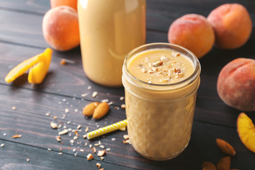 Jar with fresh peach smoothie on wooden table