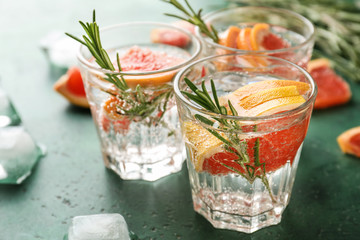 Fresh grapefruit cocktail with rosemary in glasses on color table