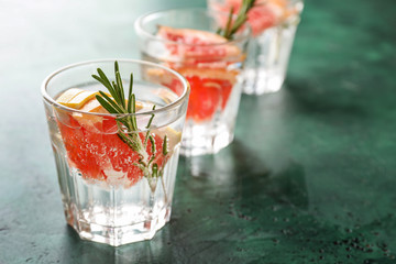 Fresh grapefruit cocktail with rosemary in glasses on color table