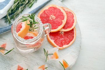 Fresh grapefruit cocktail with rosemary in mason jar on wooden board