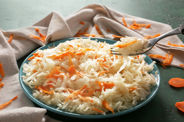 Eating of delicious sauerkraut from plate on table