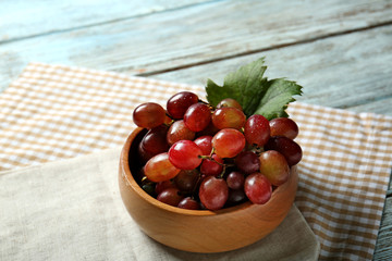 Bowl with fresh ripe grapes on wooden table
