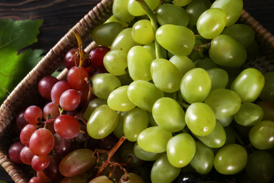 Wicker basket with fresh ripe grapes on table, closeup