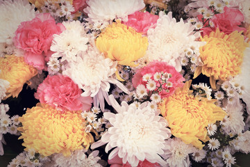 Colorful flowers arranged as a natural background image with white, yellow and pink blossoms. Vintage toned floral bouquet.
