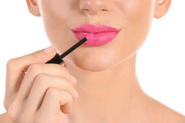 Beautiful young woman applying bright pink lipstick on white background, closeup