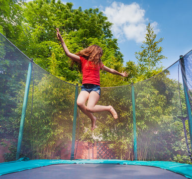 Active girl jumping on trampoline outdoors