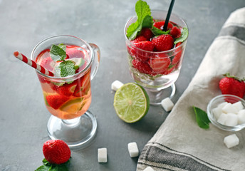 Glasses of fresh strawberry mojito on grey table