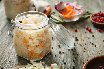 Glass jar with homemade sauerkraut on wooden table