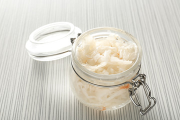 Glass jar with homemade sauerkraut on light table