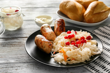 Plate with tasty sauerkraut and grilled sausages on wooden table