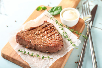 Delicious grilled steak with sauce on wooden board