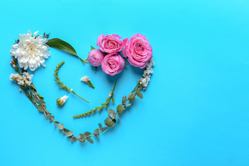 Heart made of beautiful flowers and leaves on color background