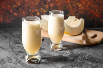 Glasses of fresh melon smoothie on grey table