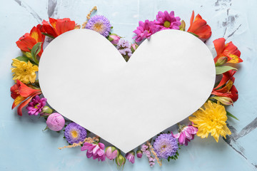 Obraz na płótnie Canvas Heart shaped sheet of paper with beautiful flowers on light background