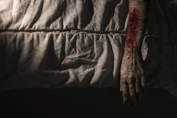 Arm of zombie woman hanging from bed