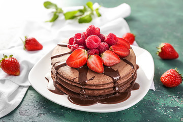 Tasty chocolate pancakes with sweet sauce and berries on plate