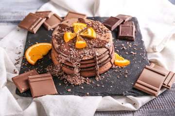 Tasty chocolate pancakes with sweet sauce and orange on slate plate