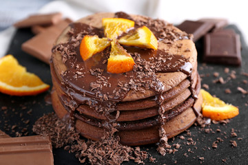 Tasty chocolate pancakes with sweet sauce and orange on slate plate