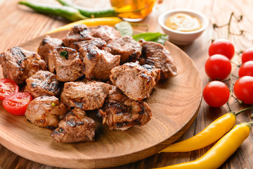 Plate with delicious shish kebab and vegetables on wooden table, closeup