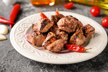 Plate with delicious shish kebab on grunge table, closeup