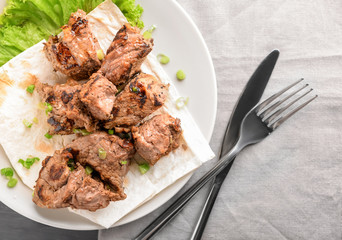 Plate with delicious shish kebab on table
