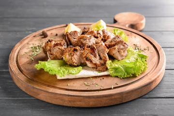 Board with delicious shish kebab on wooden table
