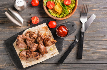 Delicious shish kebab and vegetable salad on wooden table