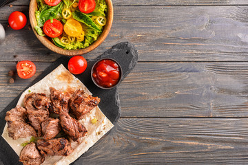 Delicious shish kebab and vegetable salad on wooden table