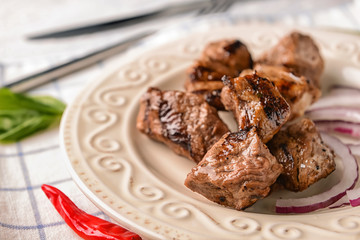 Plate with delicious shish kebab on table, closeup