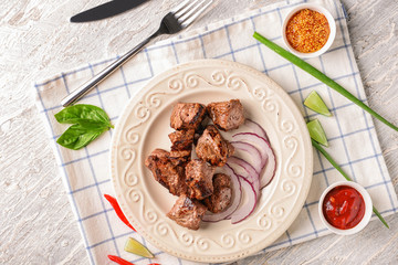 Plate with delicious shish kebab on light wooden table
