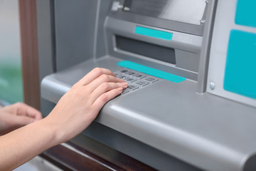 Woman entering pin code on cash machine, closeup