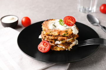 Plate with zucchini pancakes and sauce on light table