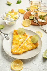 Plate with pieces of delicious lemon pie on white table