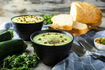 Bowls with delicious zucchini soup on grey table