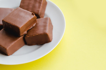 Chocolate sweets on a plate on a yellow background.