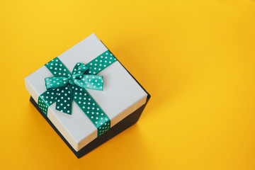 Gift box with green ribbon on yellow background. - 220103689